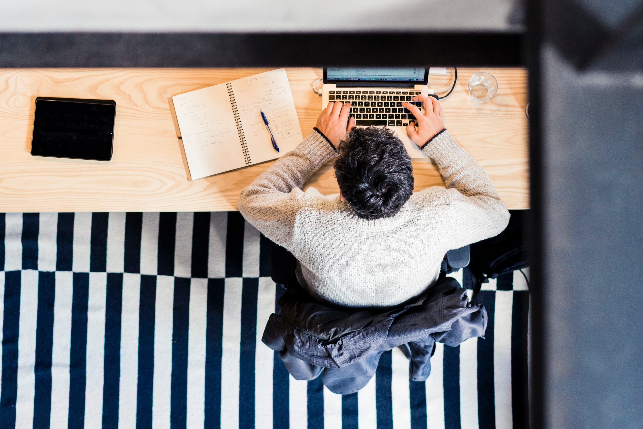 man sitting by the desk using laptop computer